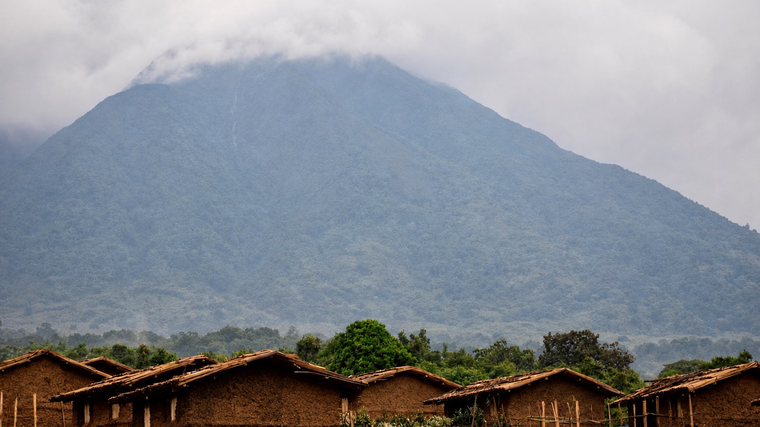 Rural homes below a cloud-covered mountain in Uganda